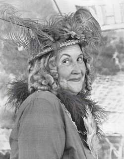 Mollie Heller wearing a feathered hat and smiling mischievously at the camera.